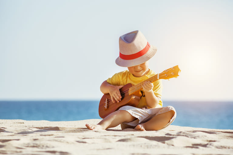 kid playing gutar on the beach